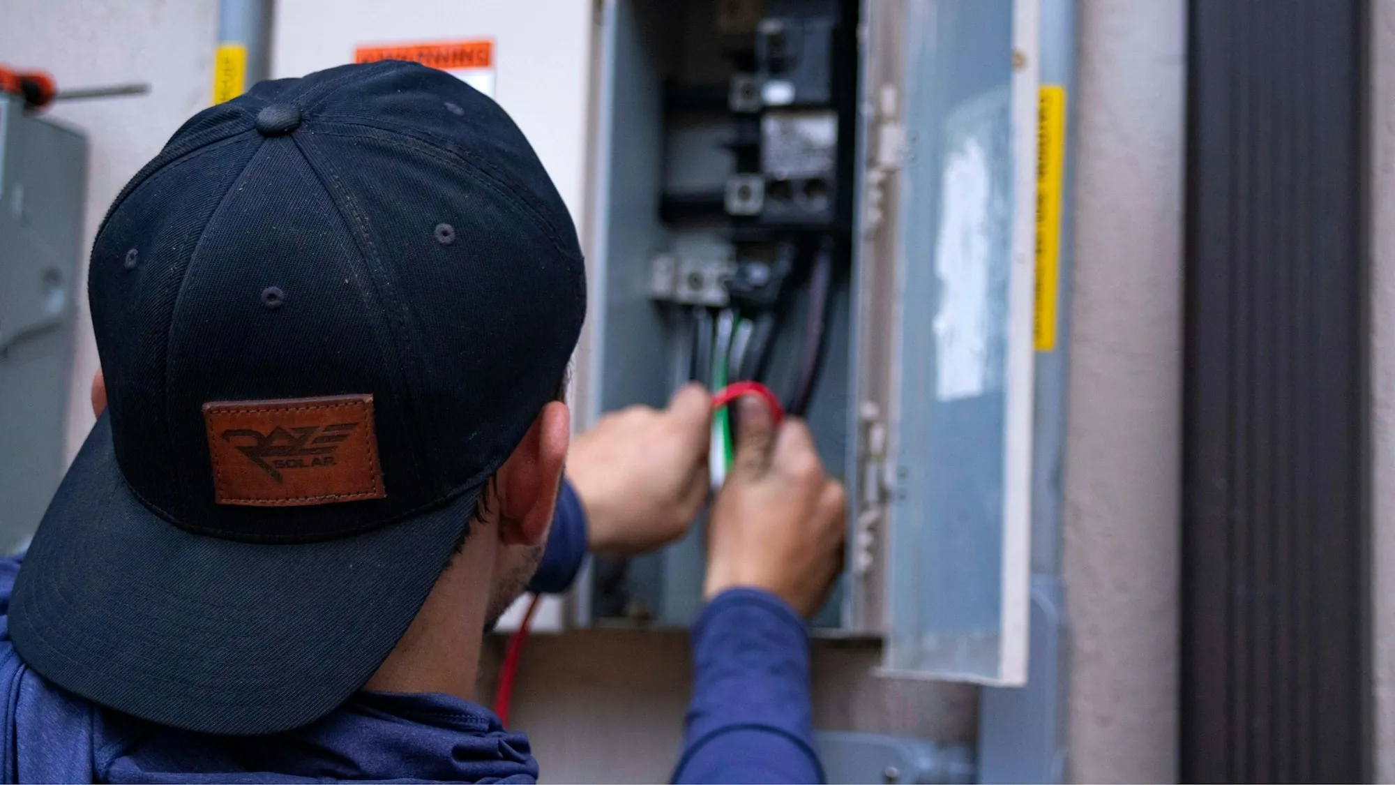 Technician working inside an open electrical panel