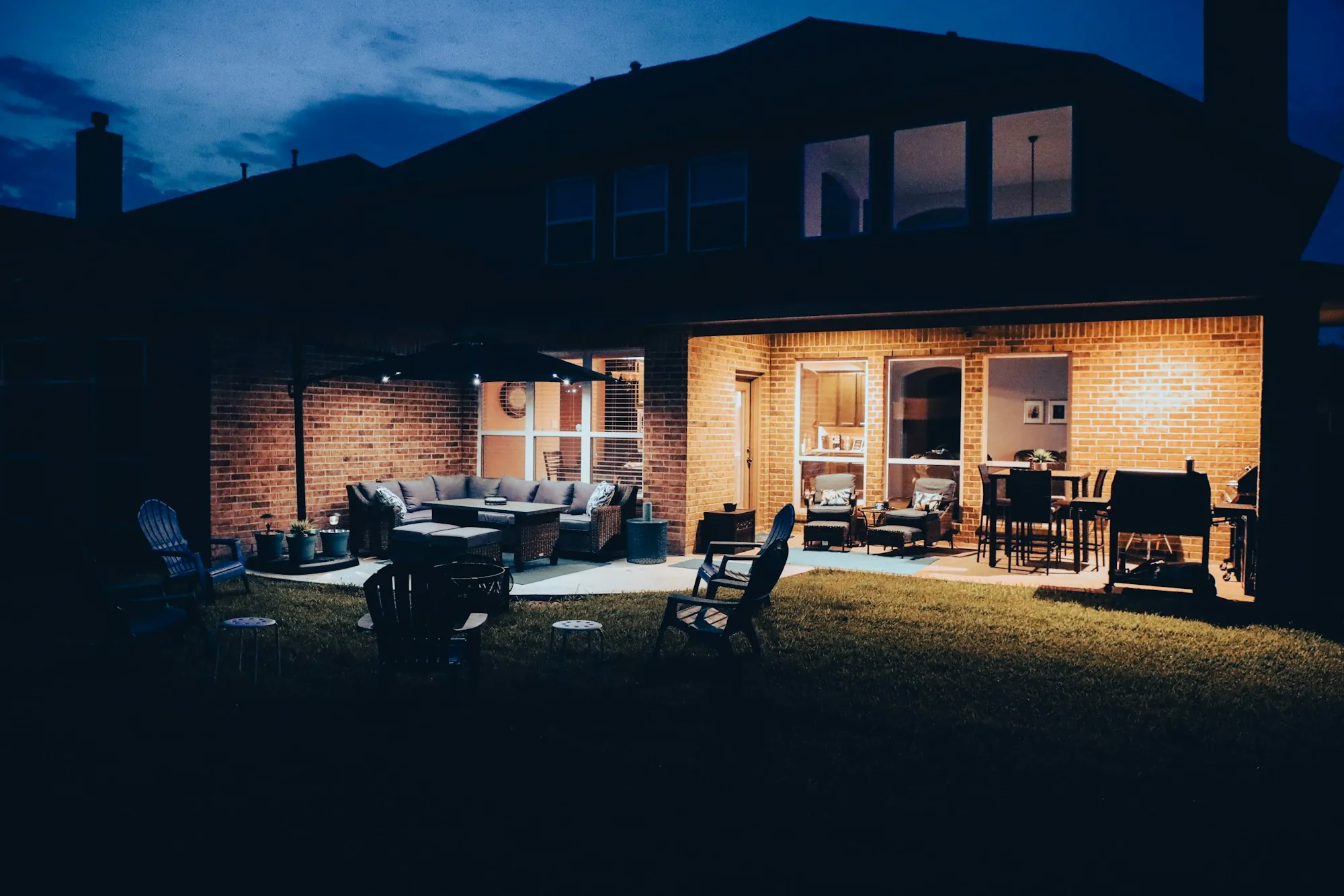 Lit back patio and brick home at night